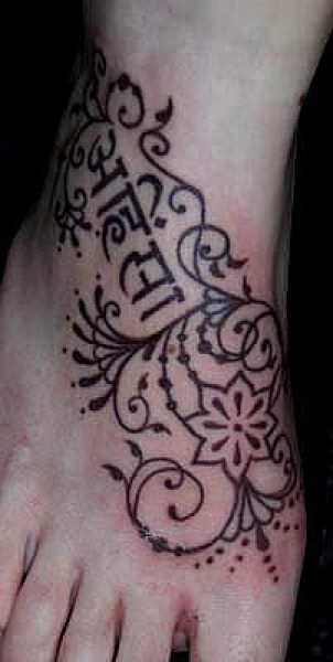 Tatuaje en el pie de sanefas y letras en sanscrito
