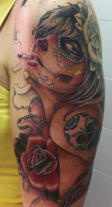 Tatuaje de una chica pintada de calavera mexicana fumando