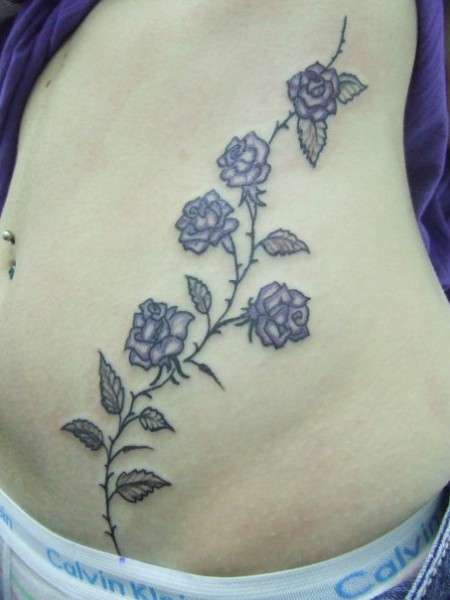 Tatuaje de unas flores que suben por la barriga