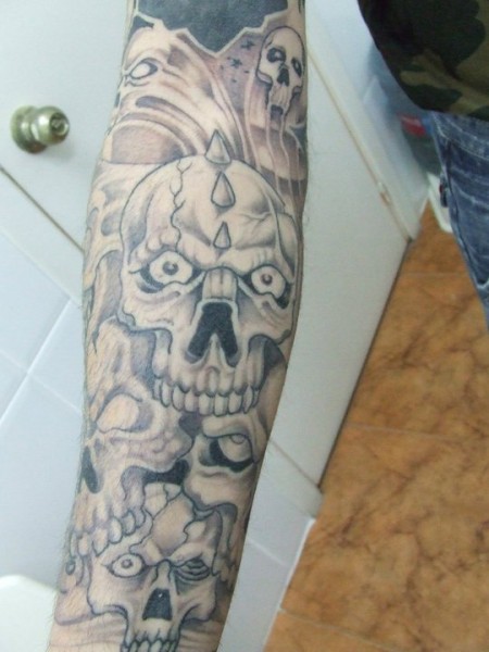 Tatuaje de muchas calaveras en el brazo