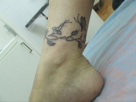 Tattoo de un pequeño brazalete de flores en el pie
