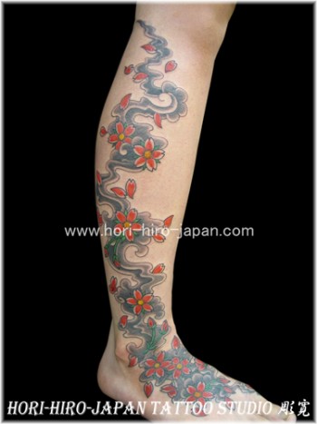Tatuajes de flores y pétalos cayendo por la pierna y posándose en el pie