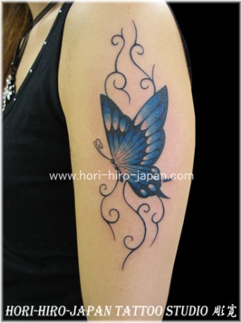 Tatuaje para mujeres, una mariposa con algunas plantas detrás