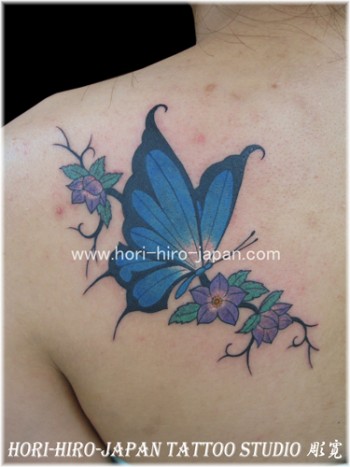 Tatuaje para mujeres, una mariposa volando entre una rama con flores