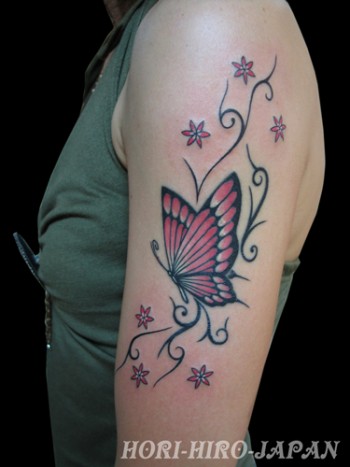 Tatuaje de mariposa con flores y tribales en el brazo