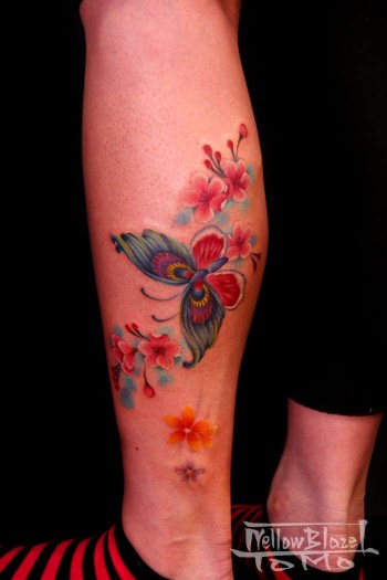 Tatuaje para mujeres de mariposa y flores en el gemelo.
