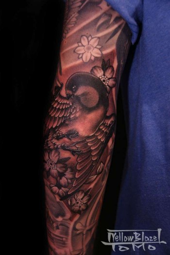 Tatuaje de un gorrión volando contra el viento con flores