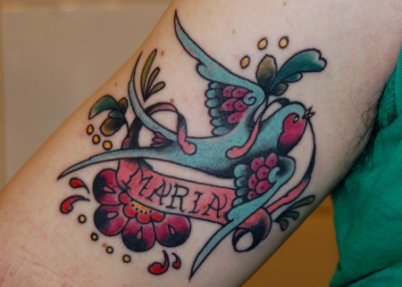 Tatuaje de una golondrina con un cartel de nombre