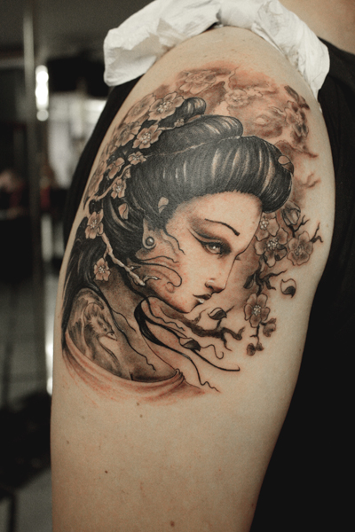 Tatuaje de una bonita cara de geisha entre ramas floridas