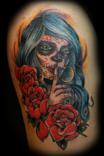 Tatuaje de una calavera mexicana haciendo silencio con varias rosas