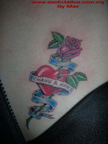 Tatuaje de un corazón atravesado por una rosa, con una etiqueta 