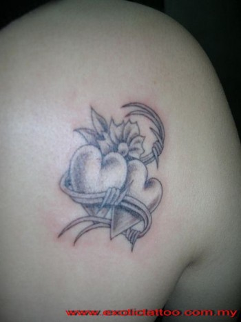 Tatuaje de dos corazones rodeados de alambre de espino y una flor