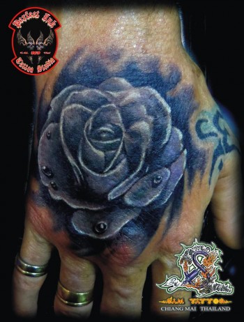 Tatuaje de una flor con gotas de agua en la mano