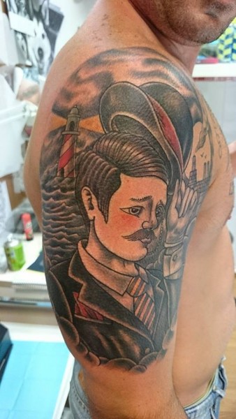 Tatuaje a color de un señor con sombrero y un faro