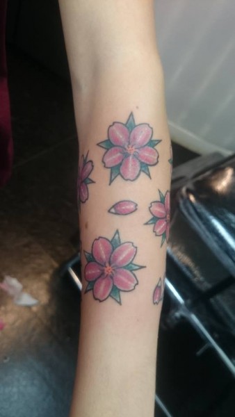 Tatuaje a color de un brazalete de flores y pétalos
