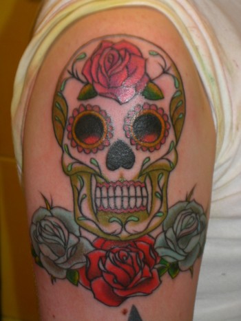 Tatuaje en el brazo de una calavera de azúcar Mexicana con tres rosas