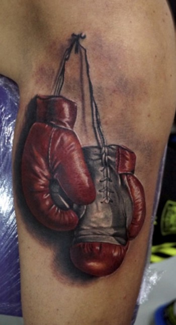 Tatuaje de unos guantes de boxeo colgados de un clavo