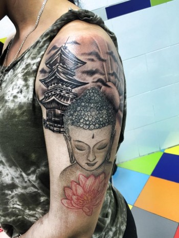 Tatuaje de un buda junto a una pagoda y un sol