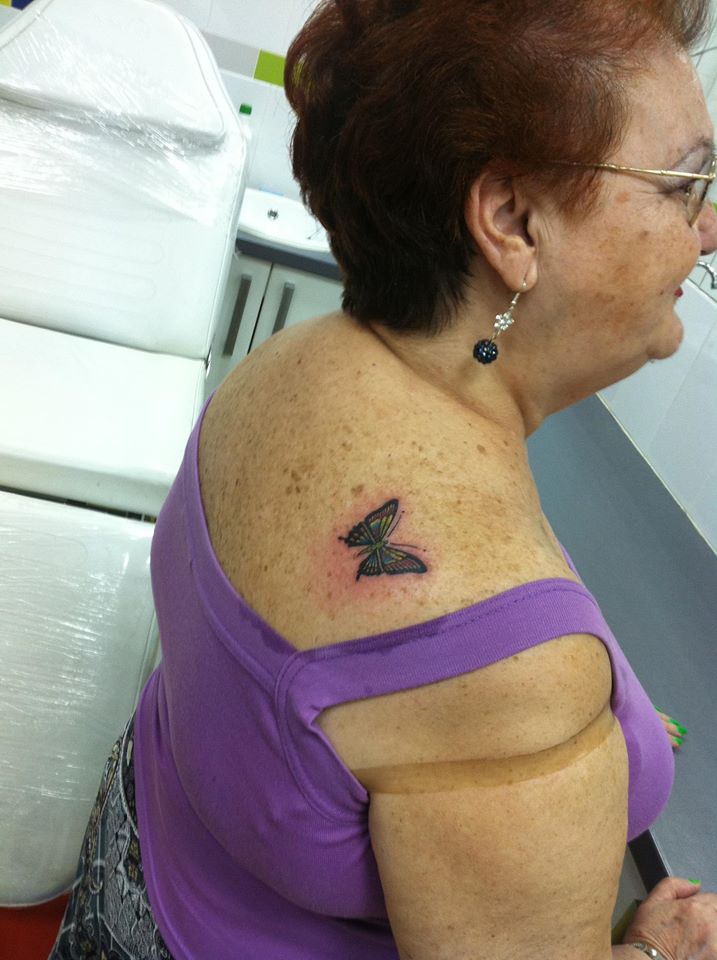 Tatuaje de una mariposa en el hombro de una señora
