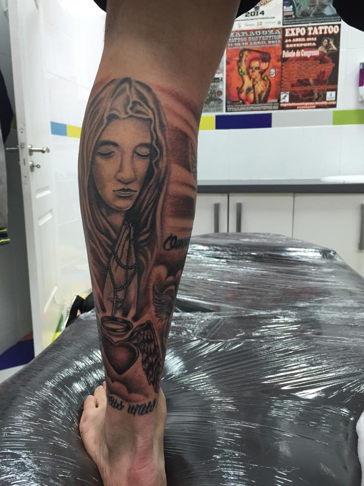 Tatuaje de una virgen rezando y un corazón con alas
