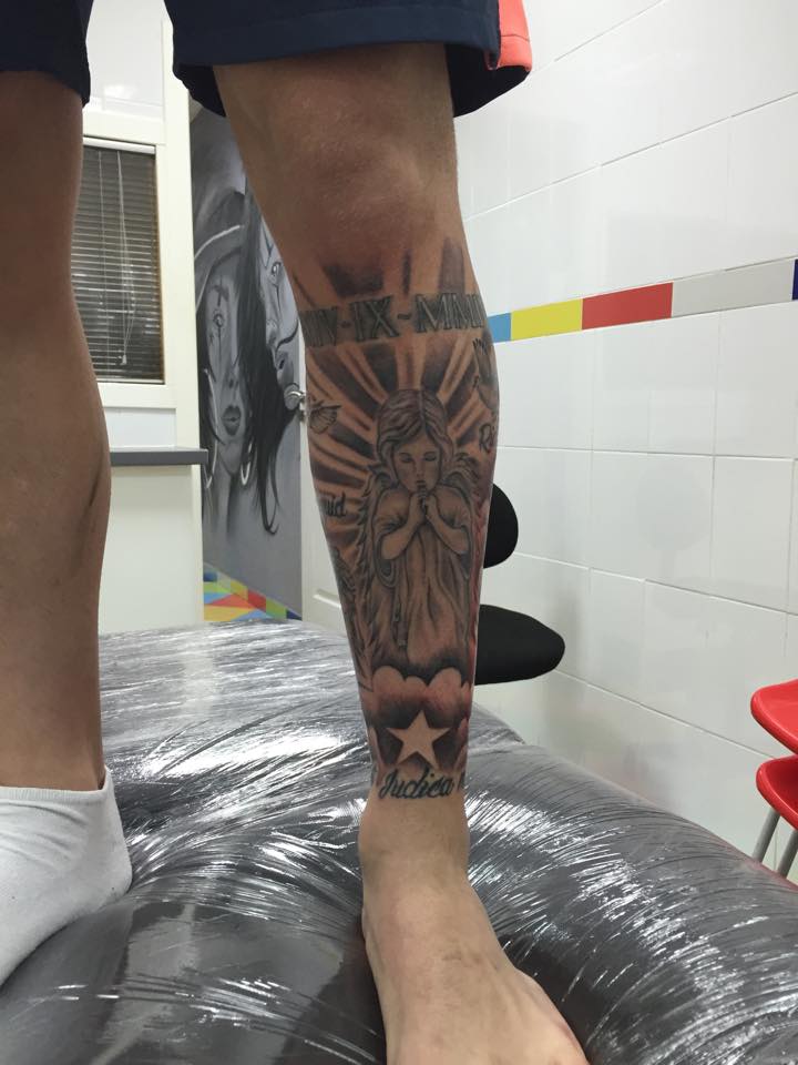 Tatuaje de un ángel con una fecha en números romanos en la pierna