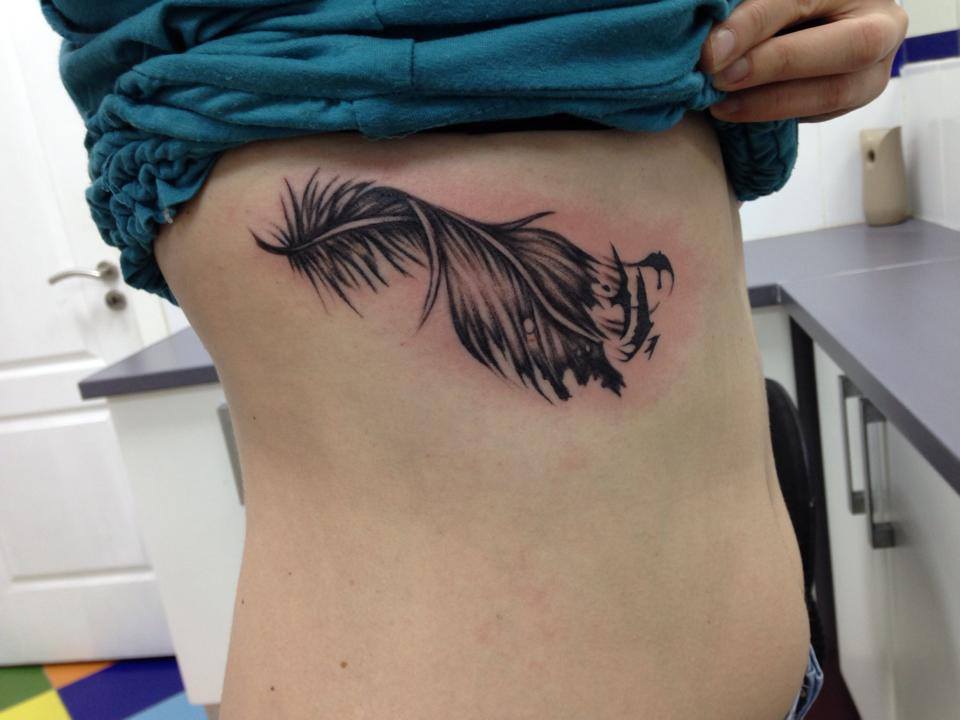 Tatuaje de una pluma en las costillas