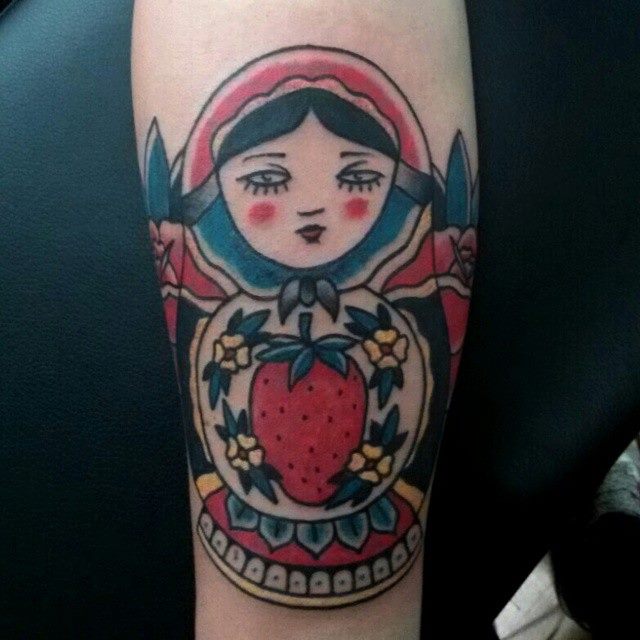 Tatuaje de una Matrioska con una fresa dibujada