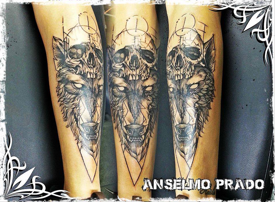 Tatuaje de un lobo con una calavera encima y símbolos geométricos