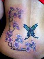 Tatuaje para mujeres de rama con flores y mariposa en la espalda