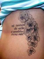 Tatuaje de unas flores en blanco y negro y una frase. Tatuaje para mujer