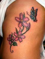 Tatuaje de una mariposa posándose en unas flores