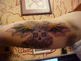 Tatuaje de una calavera con alas en la parte interior del brazo