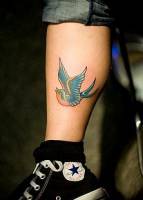 Tatuaje de una pequeña golondrina en la pierna