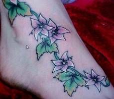 Tatuaje de enredadera con flores en el pie