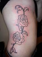 Tatuaje para mujeres de flores en el costado.