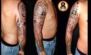 Tatuaje maorí en el brazo con un brazalete de tribales en el antebrazo