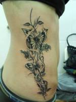 Tatuaje de flores y mariposas en el costado de una chica