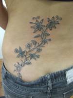 Tatuajes de unas flores subiendo por la cadera