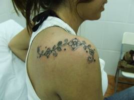 Tatuaje de florecillas en el hombro de una chica