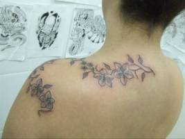 Tatuaje de unas enredaderas por los hombros de una mujer