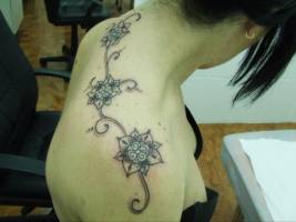 Tatuaje de tres flores en la espalda de una mujer
