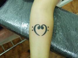 Tatuaje de dos claves de fa, formando un corazón