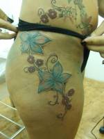 Tatuajes de unas flores por el muslo y cadera de una mujer
