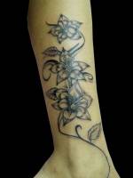 Tatuaje de tres flores subiendo por la pierna
