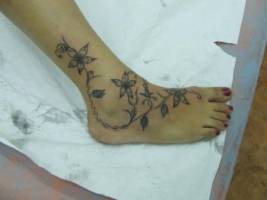 Tatuaje de unas flores por el pie
