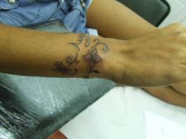 Tatuaje de una pulsera hecha con flores y finas lineas