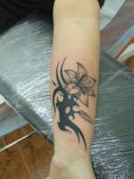 Tatuaje de una flor con el tallo de tribal