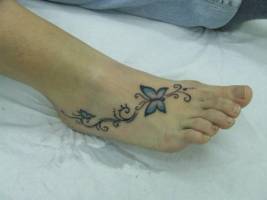 Tatuaje de unas flores y unas mariposas en el pie
