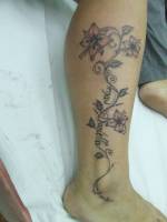 Tatuaje de unas flores en la pierna, hasta el tovillo