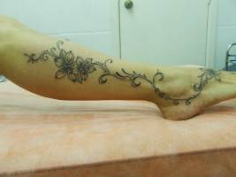 Tatuaje de unas flores con fino tallo en la pierna